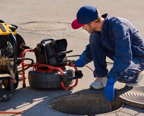 technician performing a sewer camera inspection in a road.