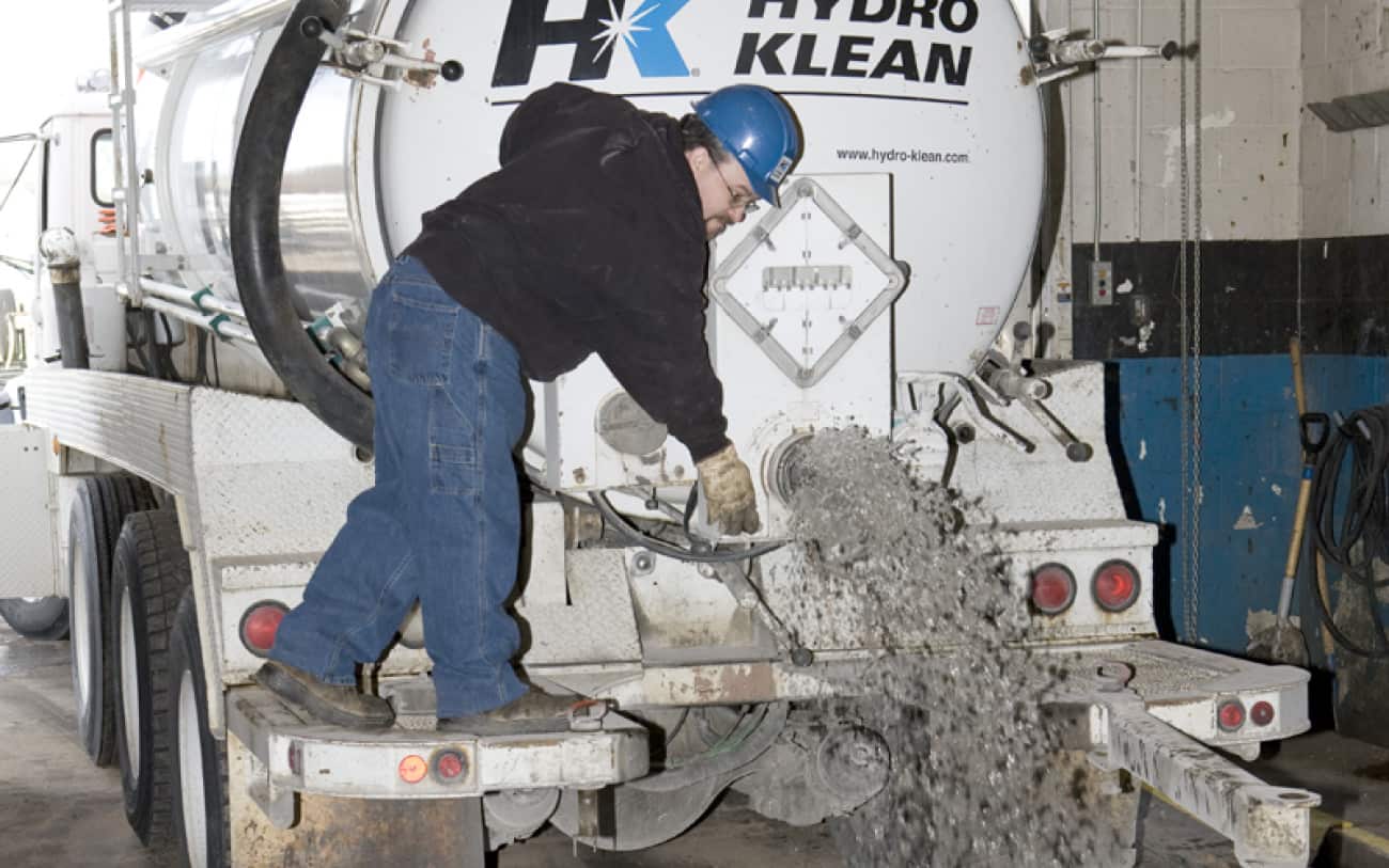 Worker releasing liquid waste from HK truck at treatment facility.